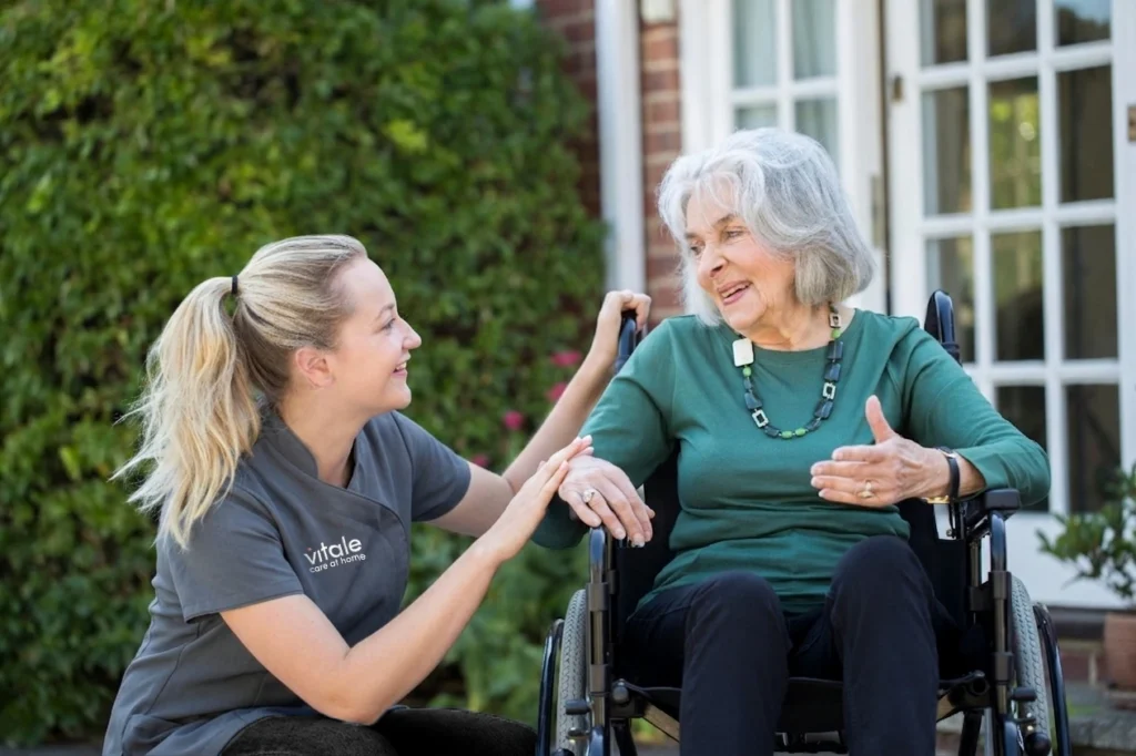 A Vitale carer with a lady sitting in a wheelchair, she is providing her with personal care.