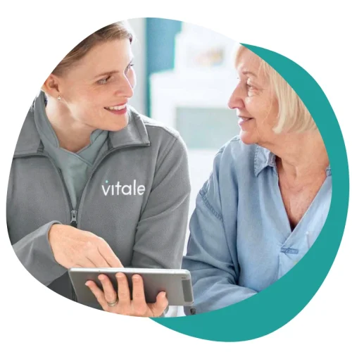 Vitale Care Professional showing an elderly lady information on a tablet